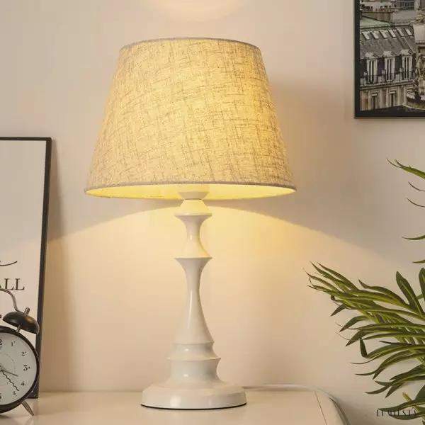 Lampa stołowa z lnianym abażurem biała - zbliżenie na gładką podstawę i miękką linię klosza