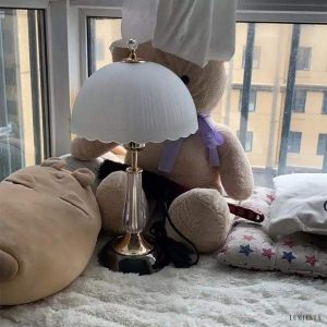 Lampa stołowa z białym, muszelkowym kloszem i złotą podstawą - widok z boku