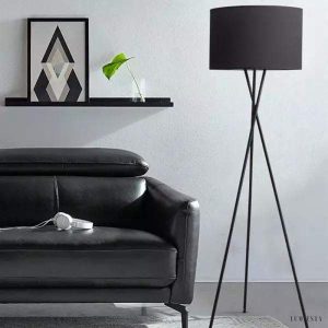 Czarna lampa stojąca LED na trójnogu do salonu, całość na neutralnym tle
