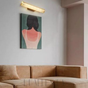 Lampa ścienna w złotym kolorze w nowoczesnym stylu - detal złotej powierzchni i cylindrycznego klosza