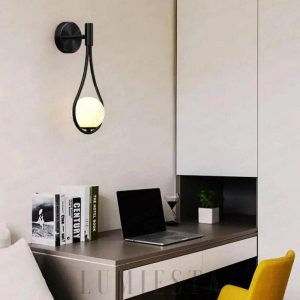 Złota lampa ścienna z kulą szklaną, detal minimalistycznej oprawy
