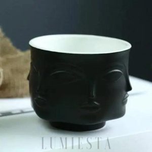 Ceramiczna doniczka w kształcie twarzy złoto czarna na neutralnym tle z pełnym widokiem formy