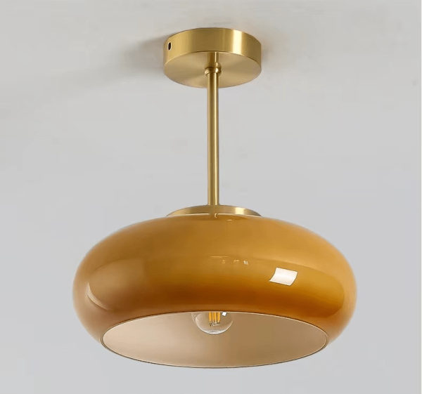 Formlicht - detal mosiężnego mocowania i pomarańczowego klosza szklanego w stylu Bauhaus